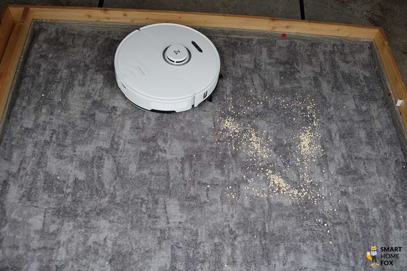 Roborock S8 Pro Ultra reinigt beim Saugtest Linsen auf einem Teppichboden.
